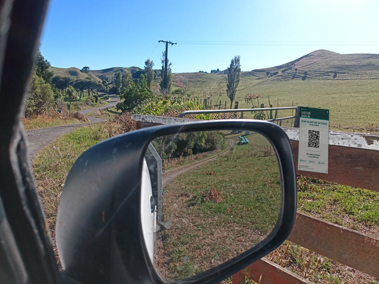 SmartSignIn QR sign on a farm gate, viewed beside a vehicle wing mirror